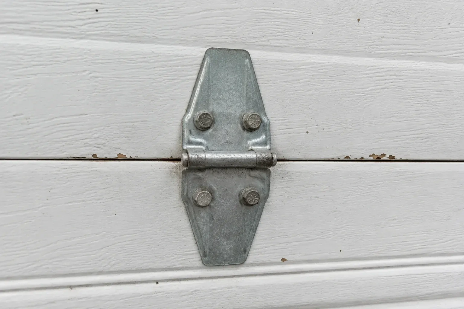 Metal center hinge across a seam in a white sectional garage door. — Garage Door Hinge Replacement, Uxbridge